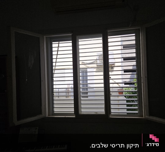 חלון עם תריסים פתוחים חלקית, אור חודר מבחוץ